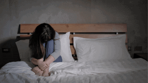 Vrouw zit depressief op bed
